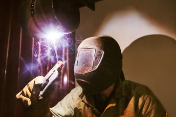 Man in protective mask welding metal construction.