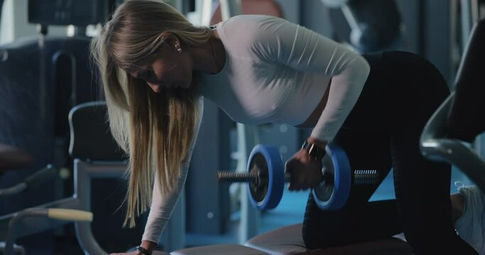 Woman lifting dumbbell at the gym for latissimus dorsi muscles