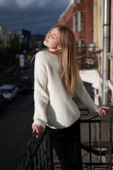 Young attractive blonde woman standing on the balcony	