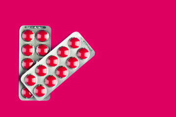 two blisters with red tablets on a red background with a copy space