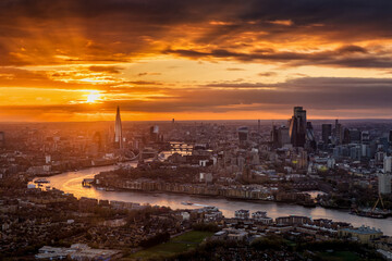 Elevated view of a beautiful sunset with orange and red colors behind the urban skyline of London, England, with River Thames and City buildings