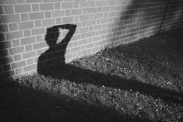 Silhouette of a human figure stands out against a brick wall backdrop - obrazy, fototapety, plakaty