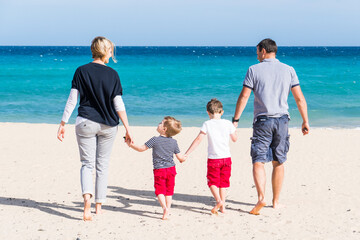 a family walking along the beach holding hands and a kite in hand