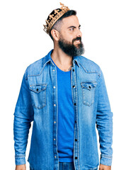 Hispanic man with beard wearing king crown looking away to side with smile on face, natural expression. laughing confident.