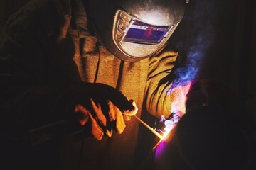 Male in mask welds metal steel, industrial shot