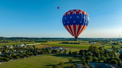 Aerial View on a Stars and Stripes, Hot Air Balloon Floating Over a Countryside Community
