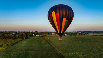 Fototapeta premium Aerial View of a Black Striped Hot Air Balloon Floating Over Fields and Farmlands in Rural America