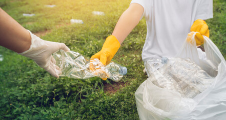 Volunteer boys and his mother help pick up plastic bottle waste at public parks for recycling,...