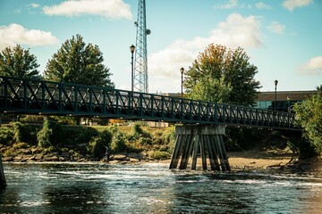 Scenic view of a metallic suspension bridge over a river on a sunny day