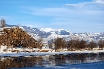 Snowcovered mountain landscape with a frozen river and cloudy sky.