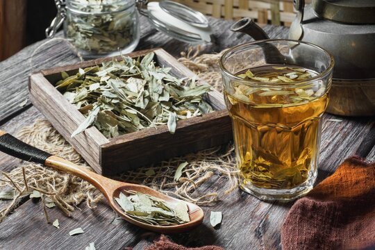 Dried senna in a bowl with a cup of tea on a wooden table