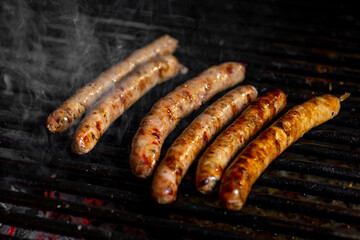 Grilling sausages on the grill with flames and smoke.