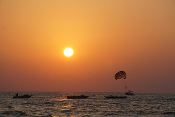 there is a man parasailing on the water with a sun setting in the