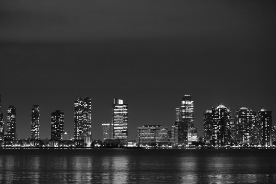 black and white image of chicago skyline from lake michigan at night with jetliner reflection