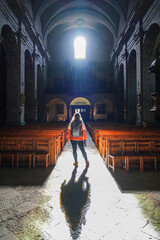 Backlit blonde woman in the central aisle of the Collegiate Church of Our Lady and Saint Nicholas of BrianÃ§on in the fortified old town built by Vauban in the French Alps - obrazy, fototapety, plakaty