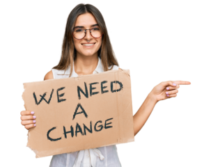 Young hispanic woman holding we need a change banner smiling happy pointing with hand and finger to the side