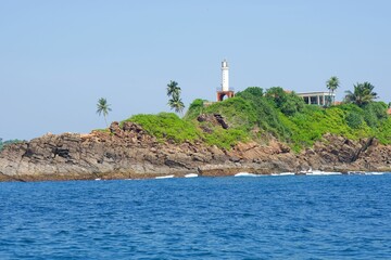 Majestic lighthouse tower on a rocky shoreline, overlooking the distant trees on the horizon