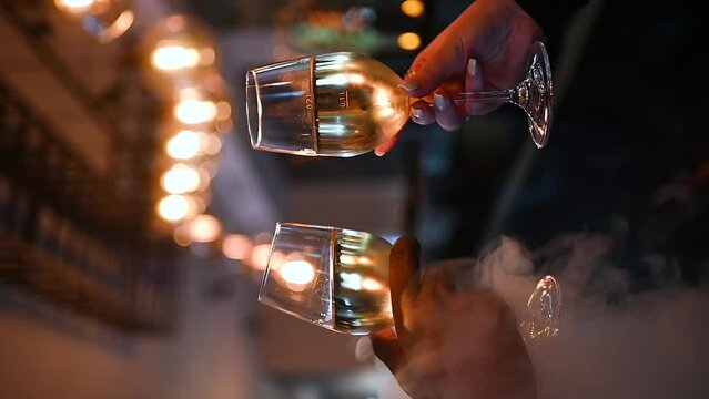 Two hands making a cheers with wine glass in a bar