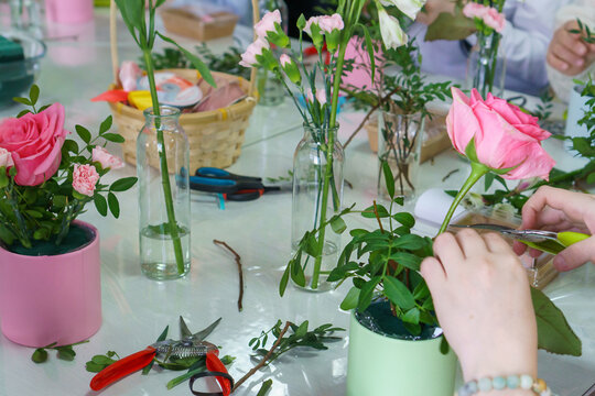 People at a master class on making bouquets of flowers in boxes. No face, just hands and a bouquet.