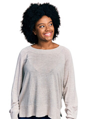 Young african american woman wearing casual clothes looking away to side with smile on face,...