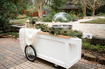 Closeup shot of a glass cotton candy container on a wooden cart decorated with pine needles - obrazy, fototapety, plakaty