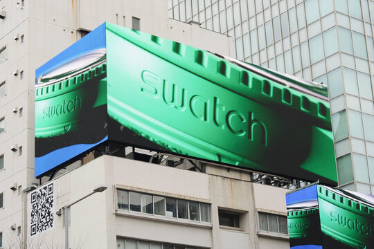 TOKYO, JAPAN - February 17, 2024: A multi-screen billboard with an advert for a Swatch watches on a building in Tokyo's Omotesando area.