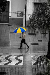 Man walking down a street holding a colorful umbrella.
