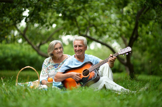 Loving mature couple with guitar in park