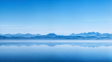 A large body of water reflecting the towering mountains in the background under a clear sky