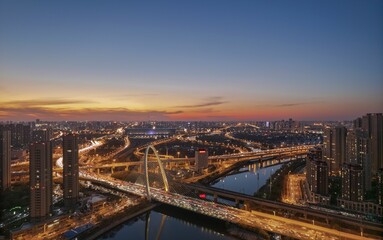 Fototapeta na wymiar Aerial shot of the Zhicheng Road Interchange over the river in Haihe, Tianjin, China at sunset