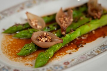 Green, fried asparagus with steamed small onions filled with mustard seeds on a spicy sauce