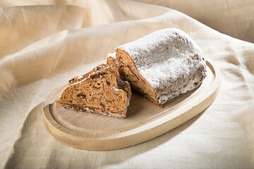 Brown wooden plate with freshly-cut slices of bread on top, resting on a beige cloth