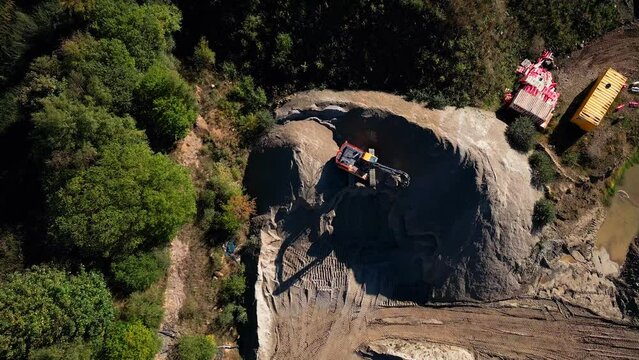 Drone footage over an excavator loading a lorry with dirt during work on sand quarry