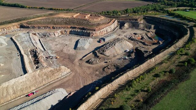 Drone footage over an excavator loading a lorry with dirt during work on sand quarry on a sunny day