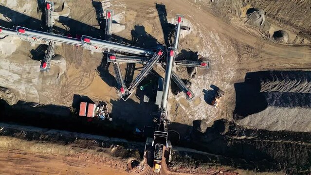 Bird's eye view over a quarry plantation with cranes and tractors digging the ground on a sunny day