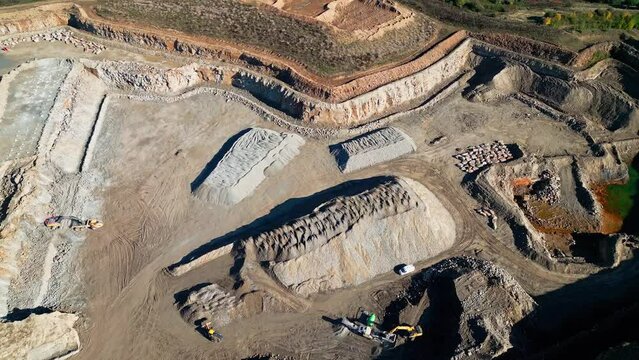 Bird eye view over an Excavator working on an open pit mine, quarry stone mining on dirt ground