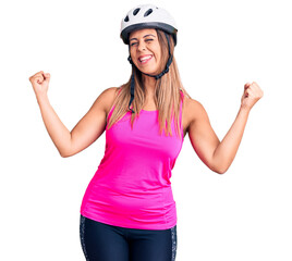 Obraz na płótnie Canvas Young beautiful woman wearing bike helmet very happy and excited doing winner gesture with arms raised, smiling and screaming for success. celebration concept.