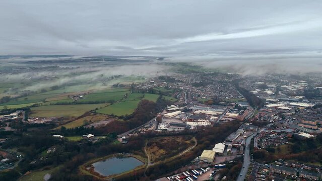Aerial of a small town in the UK on a foggy and gloomy day day with a horizon in the background