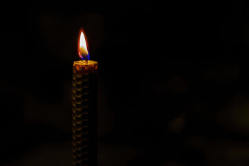 Honeycomb texture candle burning on dark background
