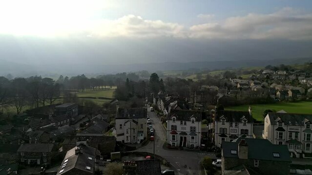Drone footage over Sedbergh town with rural houses near green hills with evening cloudy sky