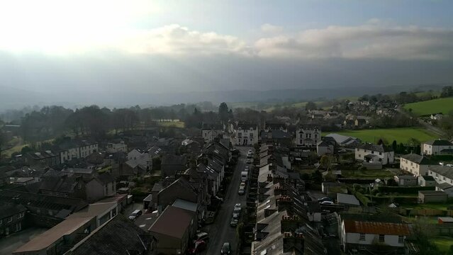 Drone footage over Sedbergh town with a mountainous view under cloudy sky