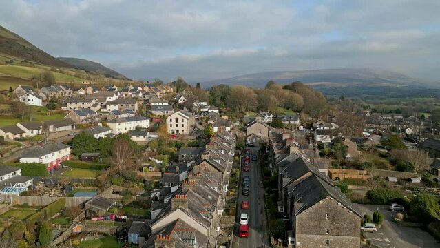 Drone footage over Sedbergh town with mountainous view under cloudy sky