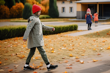 Young boy in hat and jacket walking outside school building on autumn day, Teenage autumn: a walking boy exuding autumn charm in the school yard