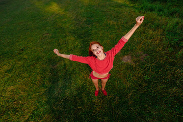 Young happy fitness woman stretching before or after workout in the morning at city park, Sporty redhead takes a break in the park after her session