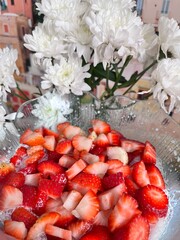 sliced red strawberries with whipped cream, sugar and flowers. Food background