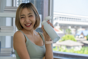 Portrait of Young Asian Sporty Smiling Woman Drinking Water After Workout at Home