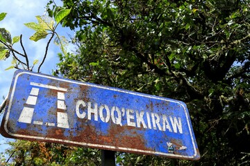 Fototapeta premium Rusty blue Choquequirao street sign on the background of lush green foliage
