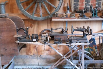 Variety of old-fashioned sewing machines and antiques inside a rustic wooden barn in New England