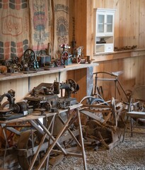 Variety of old-fashioned sewing machines and antiques inside a rustic wooden barn in New England
