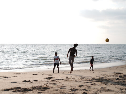 Boys and Kids playing football on the Beach 